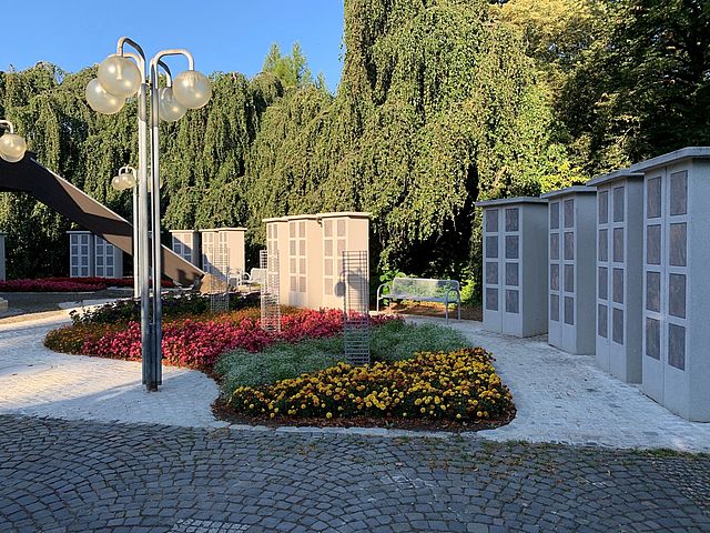 Urnenstelen auf dem Neuen Friedhof in der Heimgartenstraße in Forchheim mit Blumen im Vordergrund.
