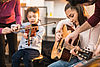 Kinder spielen Instrumente, ein Junge Geige und ein Mädchen Gitarre.