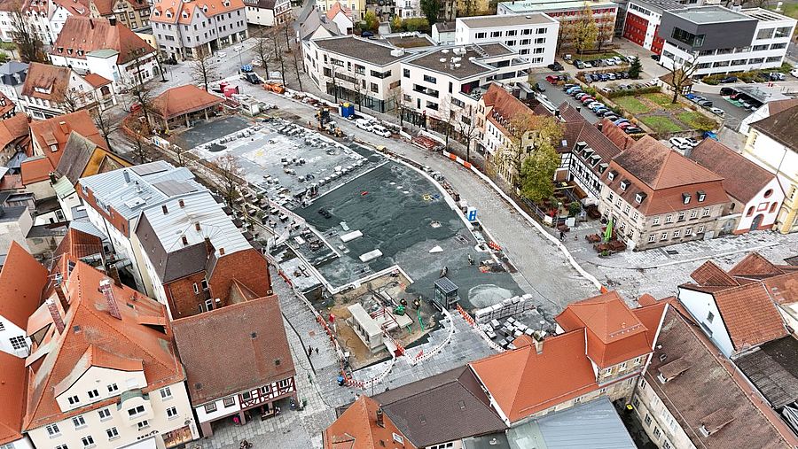 Eine Luftbildaufnahme zeigt eine Großbaustelle auf einem großen Platz in einer Stadt.