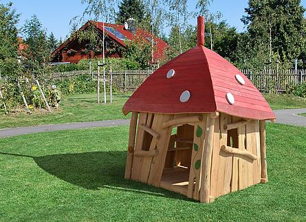 Man sieht ein Modell eines Spielhauses in Pilzoptik aus Holz für Kinder.