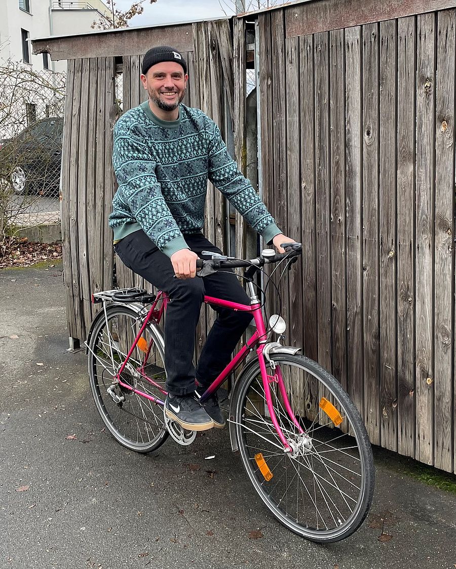 Der Radverkehrsbeauftragte Tobias Wilhelm sitzen auf einem pinkfarbenen Herrenrad.