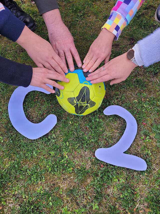 Hände auf einem Ball, welche CO2 formen.