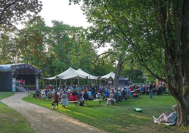 Personen lauschen einem Konzert an einem lauen Sommerabend