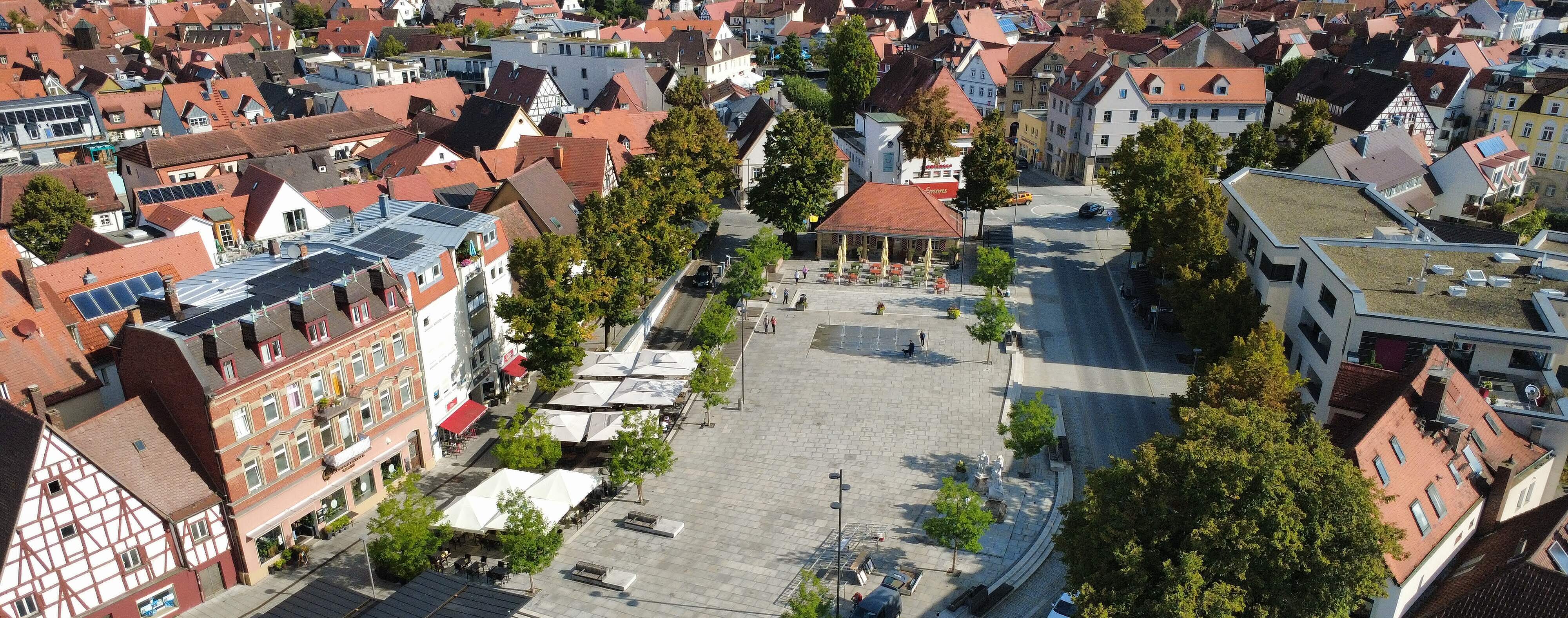 Paradeplatz Forchheim Luftbildaufnahme des Paradeplatzes im Sommer. Bäume umgeben den gepflasterten Platz mit dem Wasserspiel. Am Platzend befindet sich die "Alte Wache", ein historisches einstöckiges Sandsteingebäude mit Säulen.