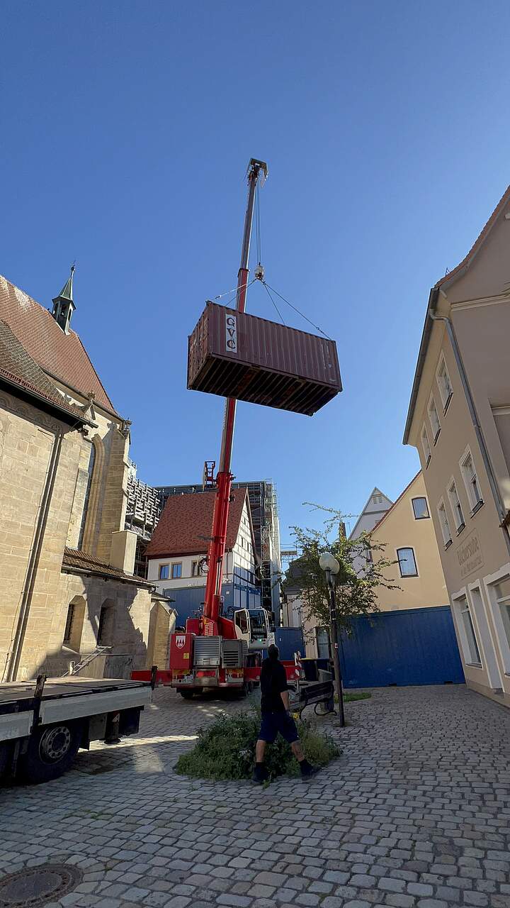 Krahn hebt Container durch enge Gassen