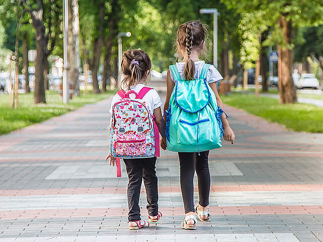 Zwei Kindergarten Kinder auf einem Gehweg von hinten.