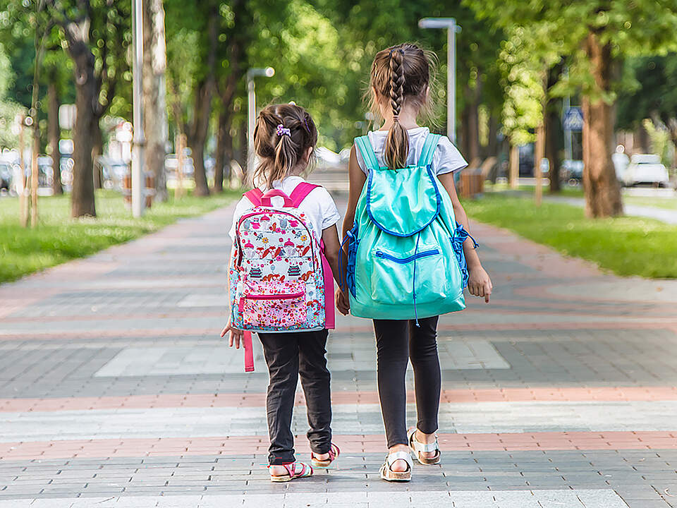 Zwei Kindergarten Kinder auf einem Gehweg von hinten.
