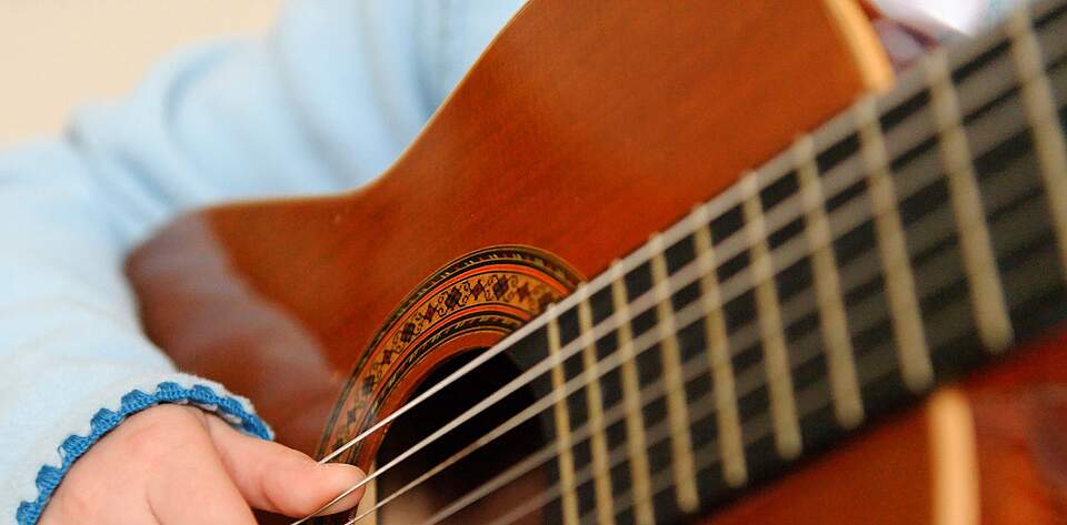 Konzert der Städtischen Sing- und Musikschule Forchheim. Man sieht den Ausschnitt eines Kinderarms mit einer Gitarre.