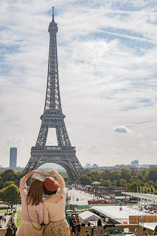 2 Frauen schauen siche gemeinsam den Eiffelturm in Paris an.