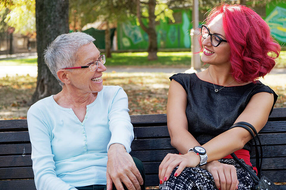 Zwei Frauen unterhalten sich auf einer Parkbank