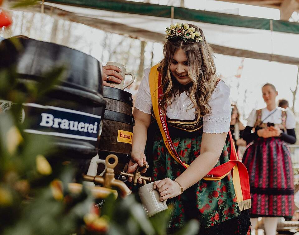 Bierkönigin Luisa I. Bierkönigin Luisa I. in Tracht und mit Schärpe Stich ein Fass Bier an.