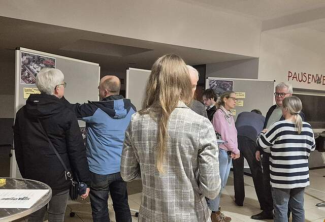 Mehrere Bürger bei einer städtischen Beteiligungsveranstaltung vor vier Stellwänden.