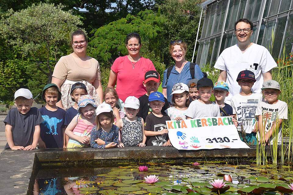 Kinder laufen für Kinder Kindertagesstätte Kersbach Gruppe mit Erwachsenen und Kindern halten ein Plakat mit einer Spendensumme in der Hand.