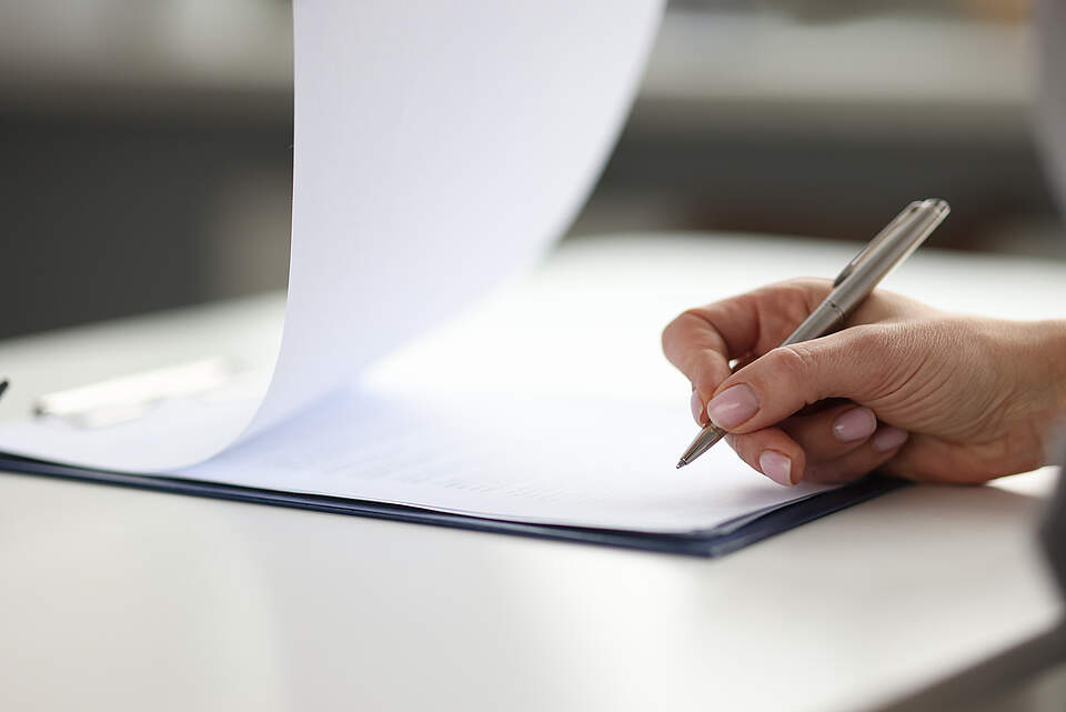 Formular ausfüllen mit Stift Eingeheftetes Formular mit einer Hand mit Stift