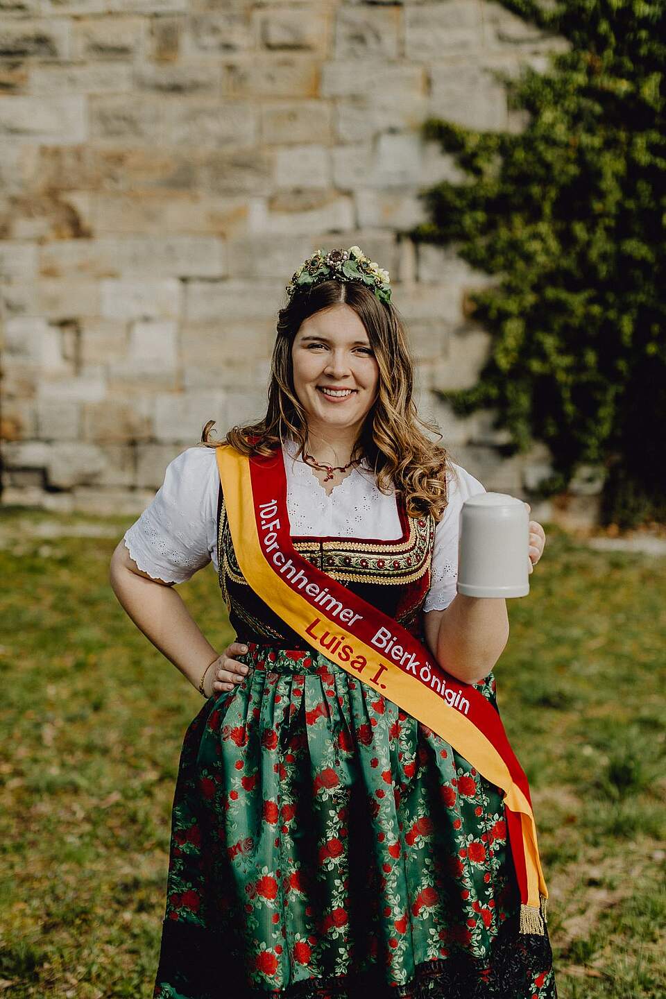 Forchheims 10. Bierkönigin - Luisa I. Eine junge Frau trägt eine fränkische bunte Tracht und eine Schärpe. Sie trägt die Krone der Forchheimer Bierkönigin.