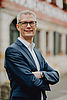 Oberbürgermeister Dr. Uwe Kirschstein steht lächelnd und mit verschränkten Armen vor dem historischen Rathaus in Forchheim.