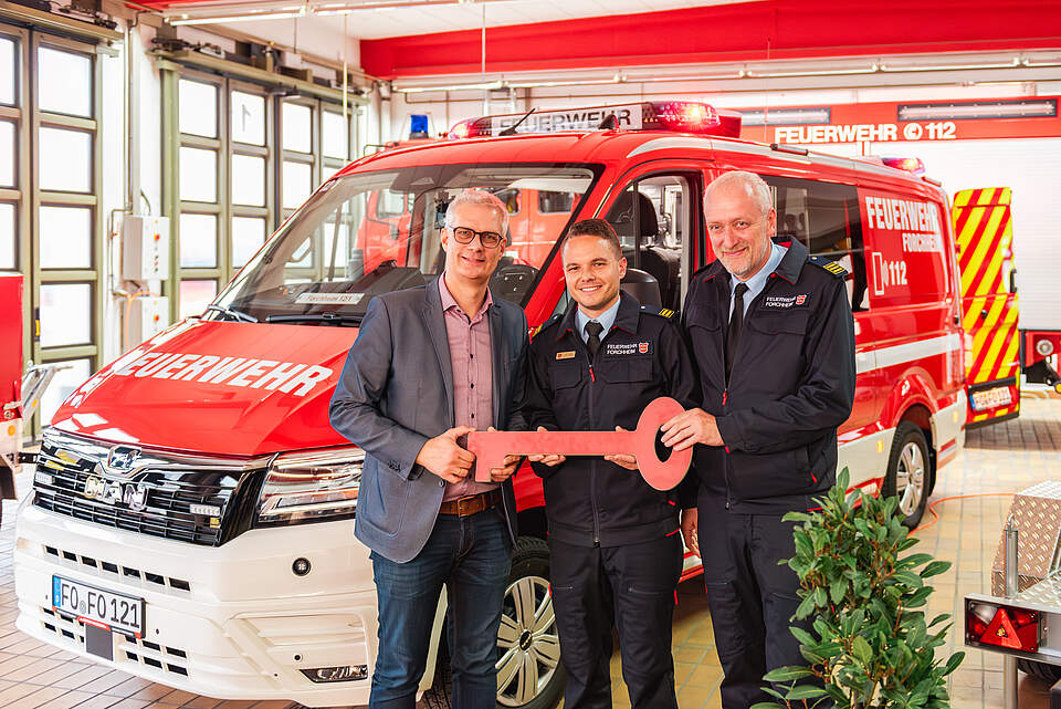 Neue Fahrzeuge für die Feuerwehr Forchheim Drei Männer stehen vor einem Feuerwehrfahrzeug bei einer symbolischen Schlüsselübergabe. Links im Bild Forchheims Oberbürgermeister Dr. Uwe Kirschstein, in der Mitte in der Kleidung der FFW Forchheim Stadtbrandmeister Timo Sokol und Kommandant Jürgen Mittermeier.