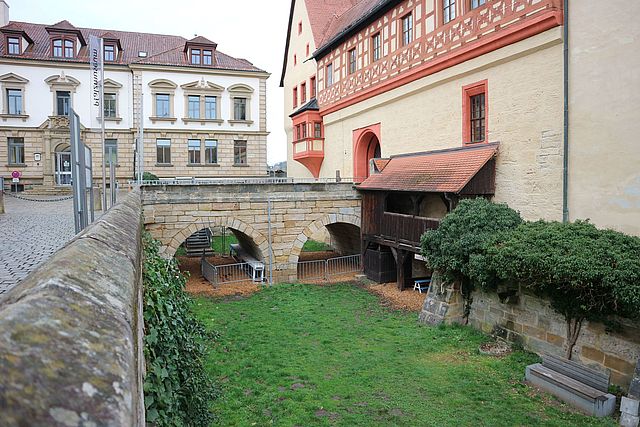 Ansicht auf die historische Steinbrücke am Eingang zur Kaiserpfalz. Im Hintergrund befindet sich ein Ausschnitt des Forchheimer Amtsgerichts. Im Burggraben stehen um die Brückenpfeiler Absperrgitter