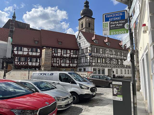 Mehrere parkende Autos am Forchheimer Rathausplatz. Im Hintergrund ein typisch fränkisches Fachwerkensemble und ein Kirchturm