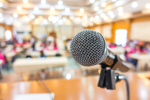 Saal mit Tischen und Mikrofon im Vordergrund