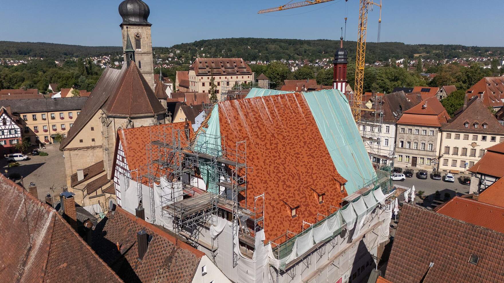 Fortgeschrittene Dachdeckungsarbeiten Luftbilduafnahme des historischen Rathauses mit den fortgeschrittenen Dachdeckungsarbeiten sowie umgebenden Häusern der Altstadt und der Kirche St. Martin.