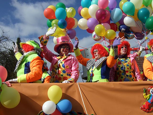 Ein Faschingsumzugswagen mit als Clowns maskierten Personen und vielen bunten Luftballons