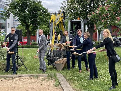 Spatenstich am Streckerplatz Der offizielle Spatenstich am Streckerplatz (v.l.): René Franz, Leiter des Stadtbauamtes, Bürgermeister Udo Schönfelder, Andreas Geck, Leiter des Amtes für Öffentliches Grün und Biodiversität, Bernd Endres, Leiter des Bereichs Planung und Bau der Regierung von Oberfranken, Bürgermeisterin Dr. Annette Prechtel und die Leiterin des Amtes für Stadt- und Verkehrsplanung/ Umwelt- und Naturschutz, Corinna Stirnweiß. Im Hintergrund befinden sich große Bäume und ein Ausschnitt des Gebäudes des Landratsamtes Forchheim