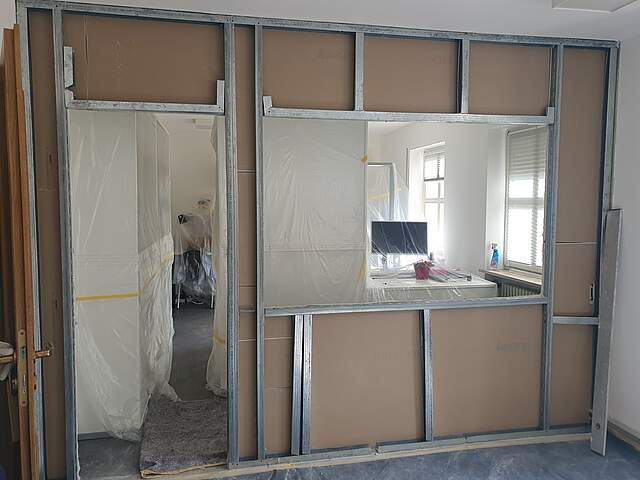 Ein Innenausbau in einem Gebäude mit Fenster und Türaussparung zum angerenzenden Raum.