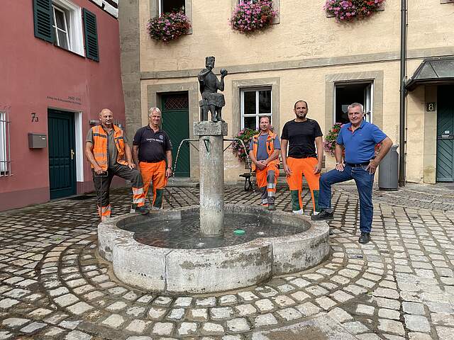 Fünf Mitarbeiter des Forchheimer Bauhofs stehen um den Konradsbrunnen vor dem Verwaltungsgebäude in der St.-Martin-Straße.