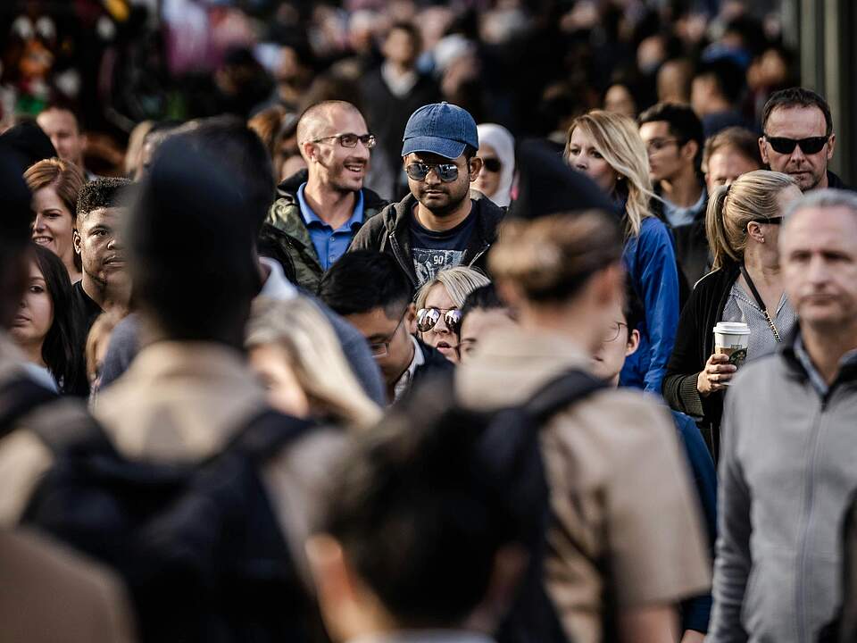 Mikrozensus Personen in einer Menschenmenge sind in der Mitte fokussiert, im Vorder- und Hintergrund verschwommen zu sehen.
