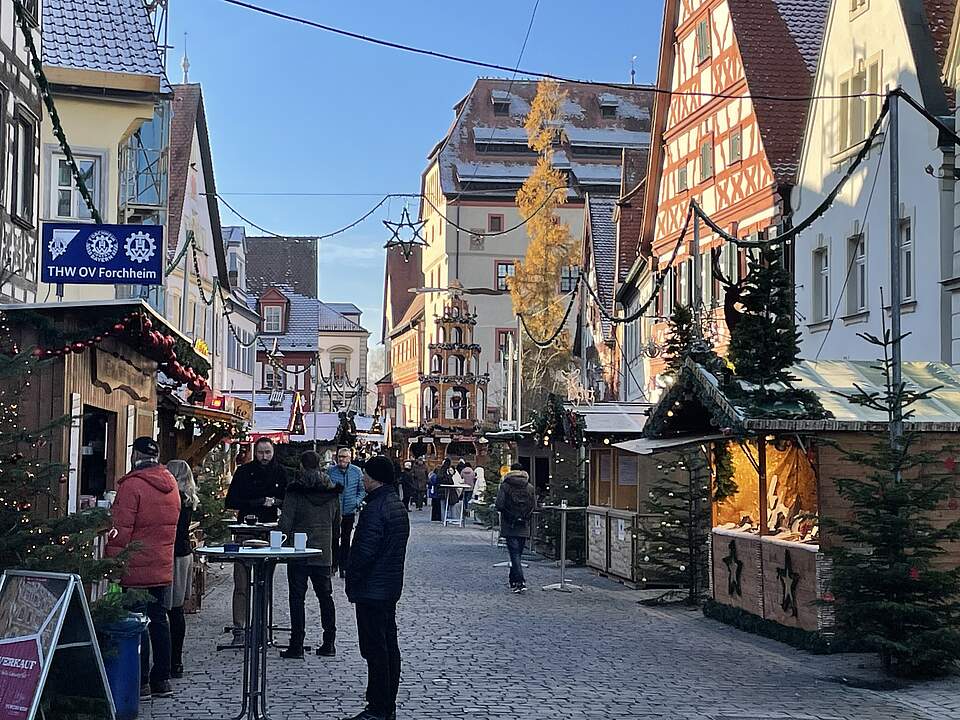 Weihnachtsmarkt in Forchheim Ein Weinnachtsmarkt mit geschmückten Buden und weihnachtlicher Beleuchtung umrahmt von Stadthäusern und den mächtigen Bau der Kaiserpfalz Forchheim.