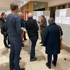 Bürgerinnen und Bürger diskutieren gemeinsam mit der Verkehrsplanung die vorgeschlagenen Varianten im Foyer vor zwei Pinnwänden
