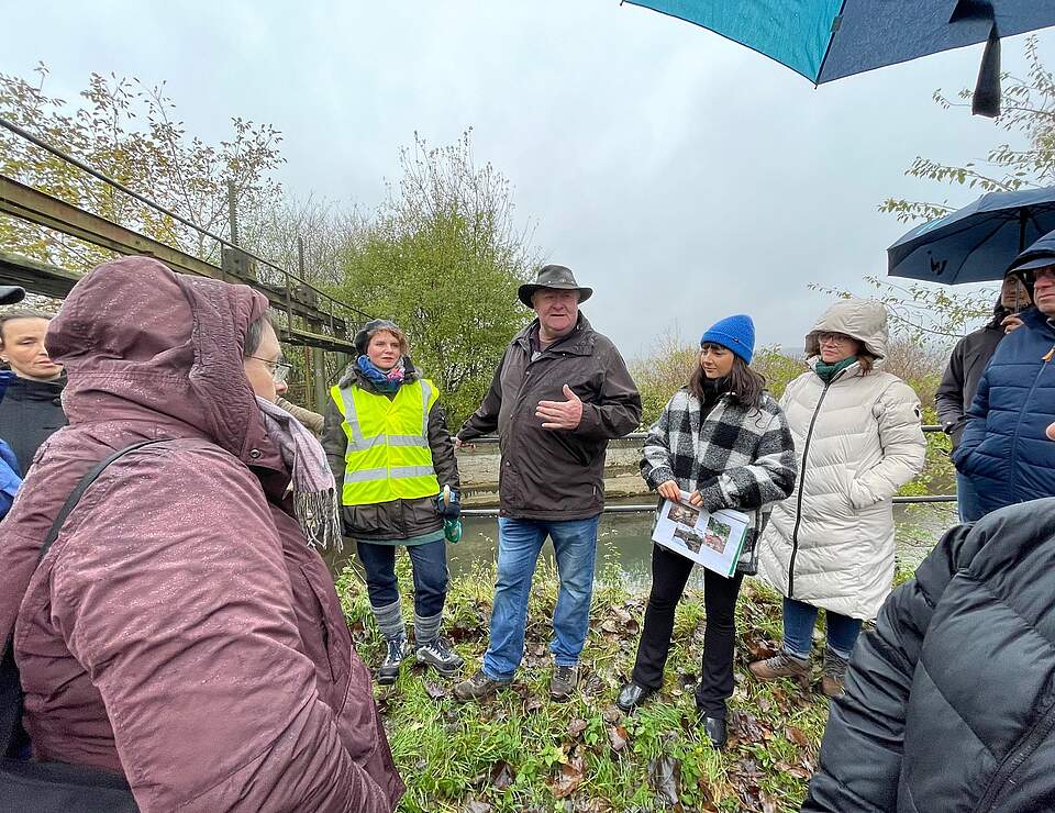 Besuch bei den Forchheimer Wässerwiesen Forchheims Wassermanagerin Julia Schrade (Bildmitte mit Warnweste) mit der Besuchergruppe aus dem Landkreis Weißenburg-Gunzenhausen und den Fachleuten vom Wasserwirtschaftsamt Ansbach an einem Wehr im Gebiet der Forchheimer Wässerwiesen.