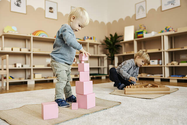 Kita Kinder spielen mit Holzspielzeug und lernen dadurch das Spiel.