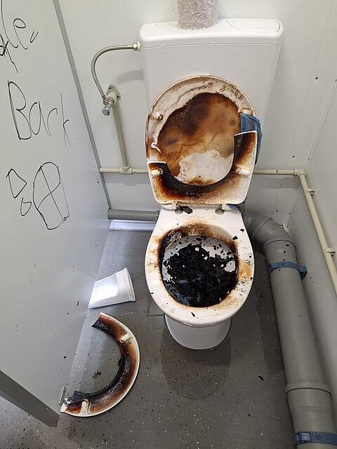 Eine verwüstete Toilettenanlage mit herausgerissenem Klopapier aus der Halterung, verstopften Leitungen und abgefackelter Klobrille auf der Sportinsel.