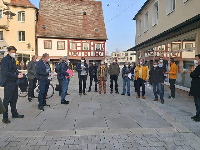 Eine Gruppe Erwachsener begutachtet eine neugestaltete Pflasterfläche.e.