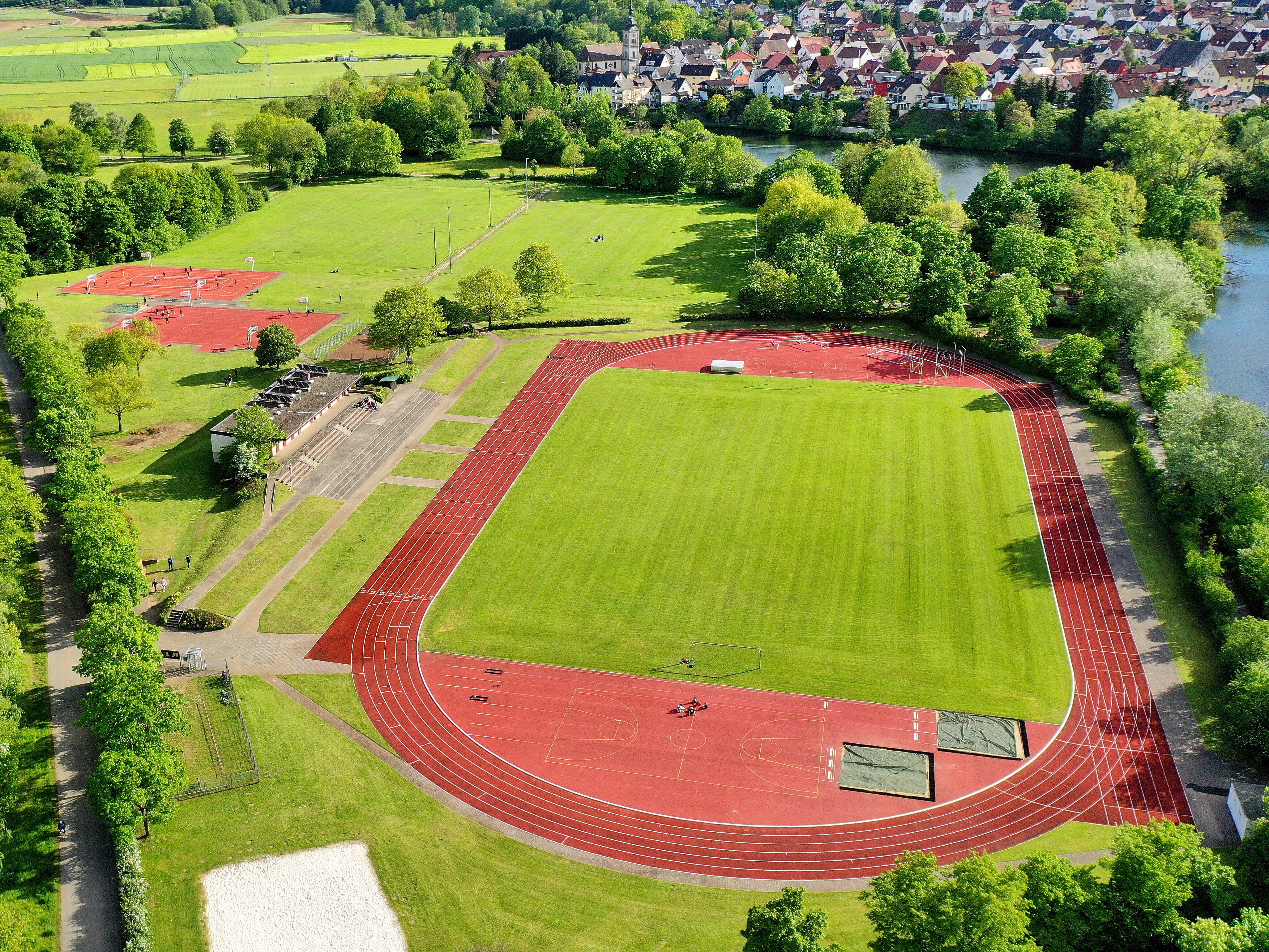 Luftbildaufnahme der Sportinsel in Forchheim mit Fußballfeld, Lauftbahn und weiteren Outdoorsportanlagen. Die große Grünanlage ist von zwei Seiten umgeben von Flüssen.