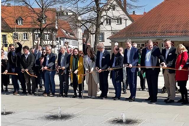 Feierliche Eröffnung der Wasserspiele am Paradeplatz, bei der mehrere Personen ein Band durchschneiden