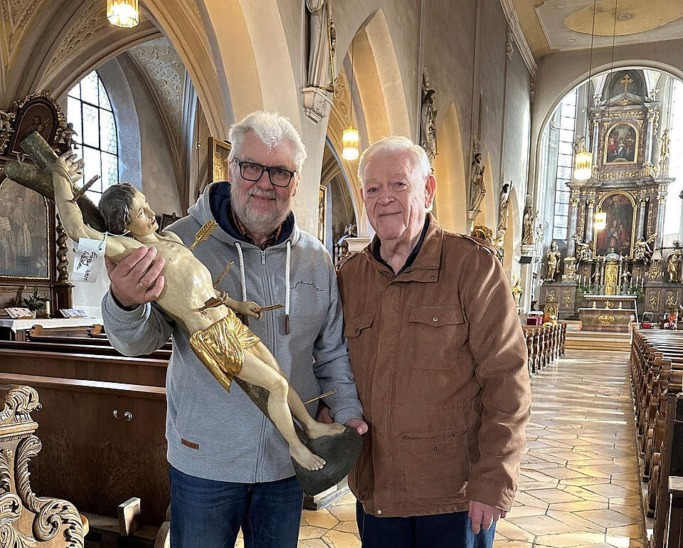 Zwei Personen in einer Kirche  mit einer Figur des heiligen Sebastians