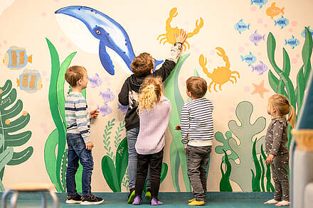 Kindergartenkinder vor bunter Wand