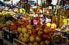 Ein Marktstand mit frischem Obst, Nüssen, Honiggläsern und Kräuterölen. 