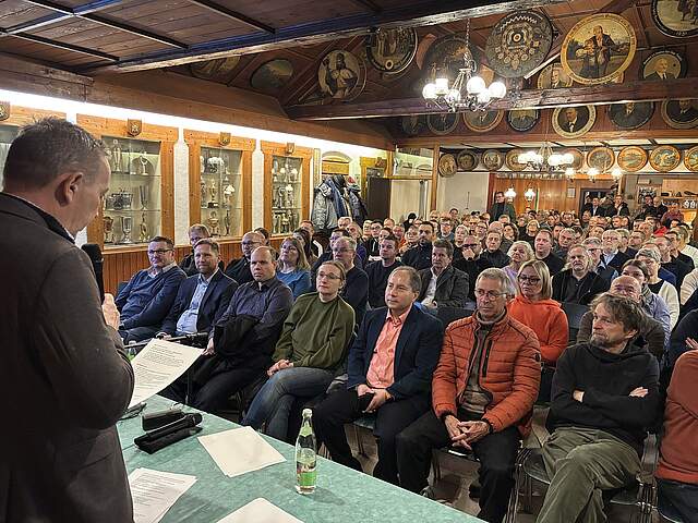 Raum mit Vortragendem und gut besuchtem Publikum