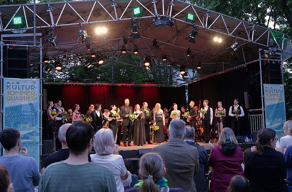 Odessa Symphony Orchestra in Forchheim Ein Orchester spielt auf einer Open-Air-Bühne, im Vordergrund sind Zuschauer zu sehen.