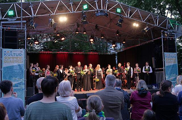 Menschen vor einer Bühne bei einem Open-Air-Konzert