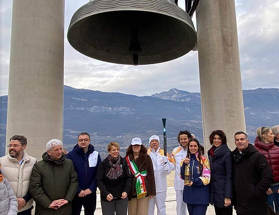 Mehrere Personen stehen vor der Friedensglocke in Rovereto