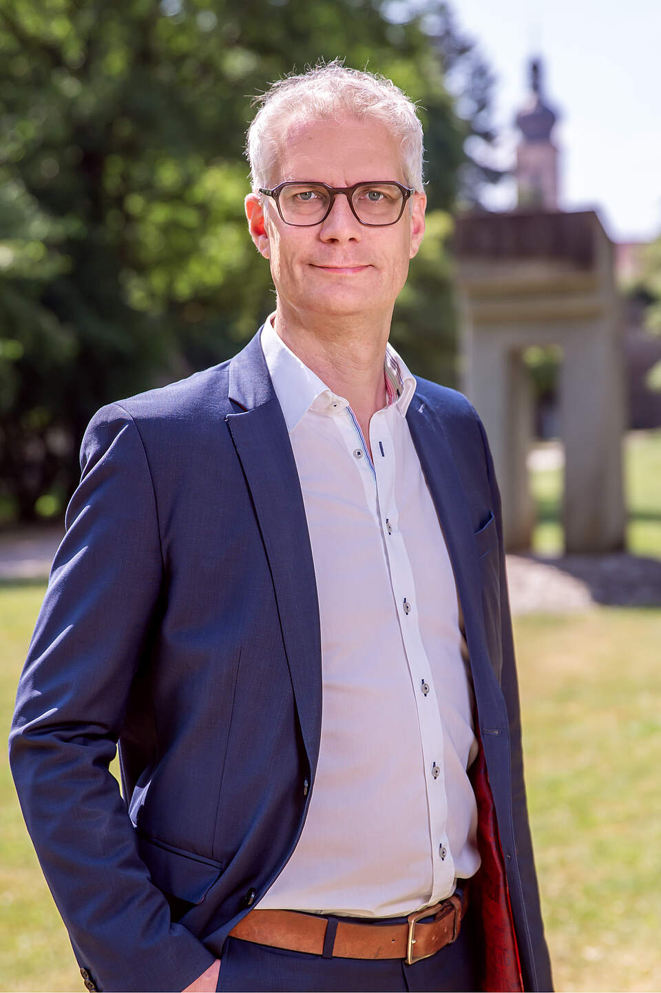 Oberbürgermeister Dr. Uwe Kirschstein im Stadtpark. Im Hintergrund stehen große Bäume und ein Denkmal.
