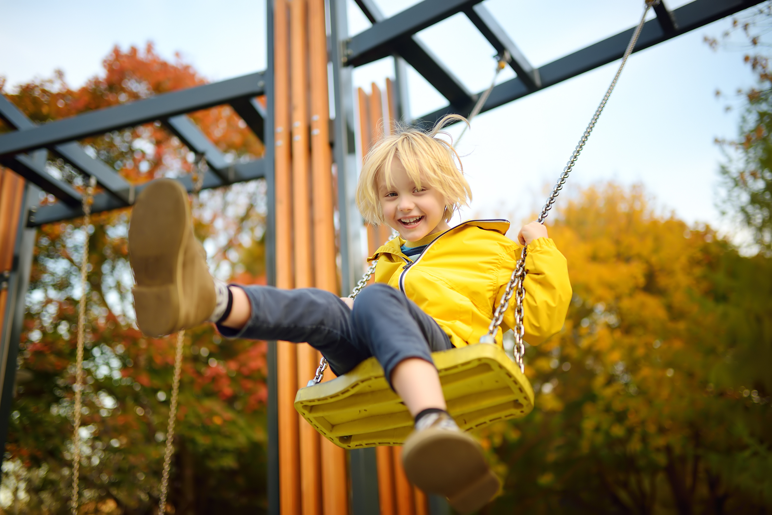 Ein Junge hat Spaß beim Schaukeln auf einem Spielplatz an einem herbstlichen Tag.