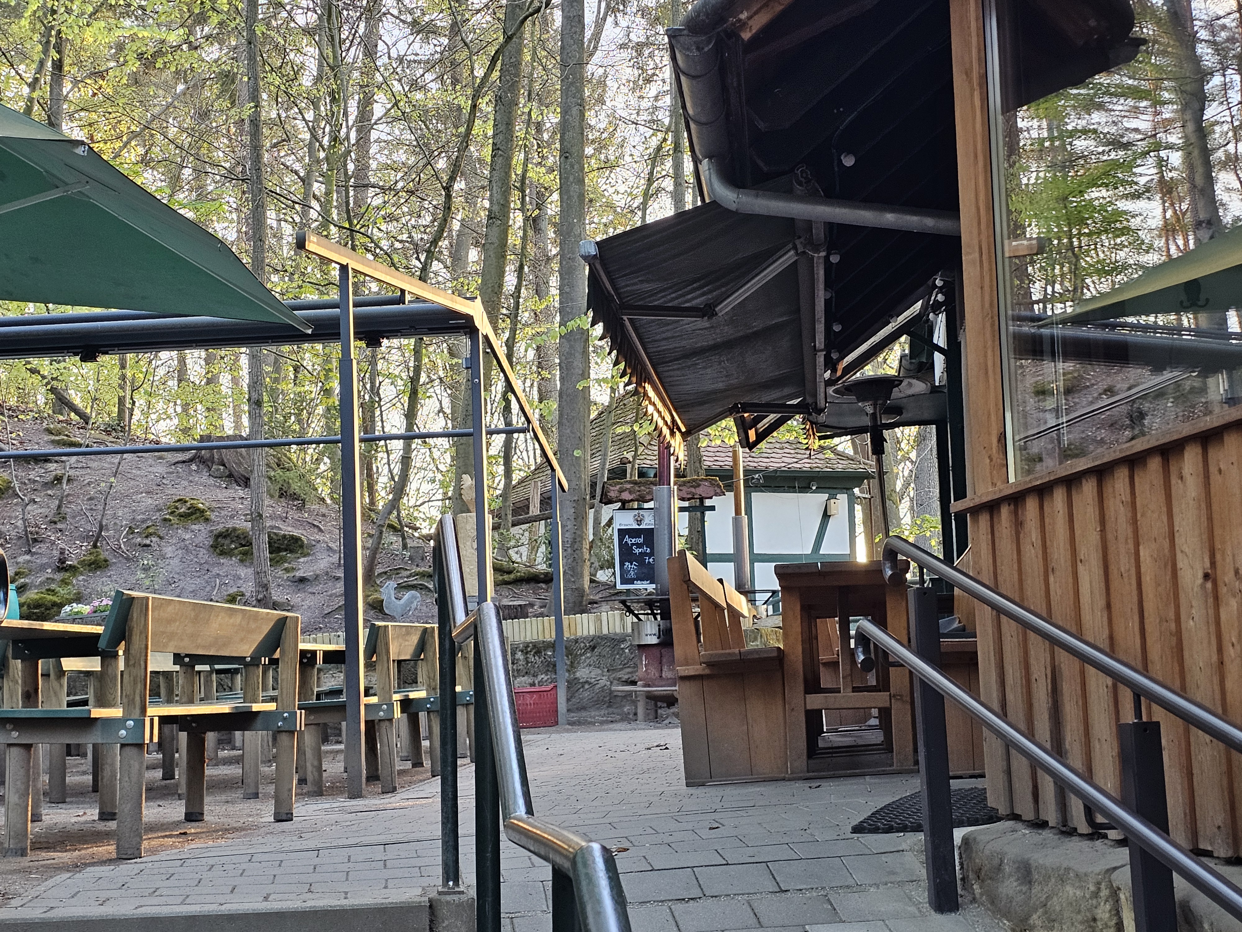 Aufgang mit Blick auf mehrere Biergarnituren, Schonnenschutz und dem Anbau des Glockenkellers im Forchheimer Kellerwald