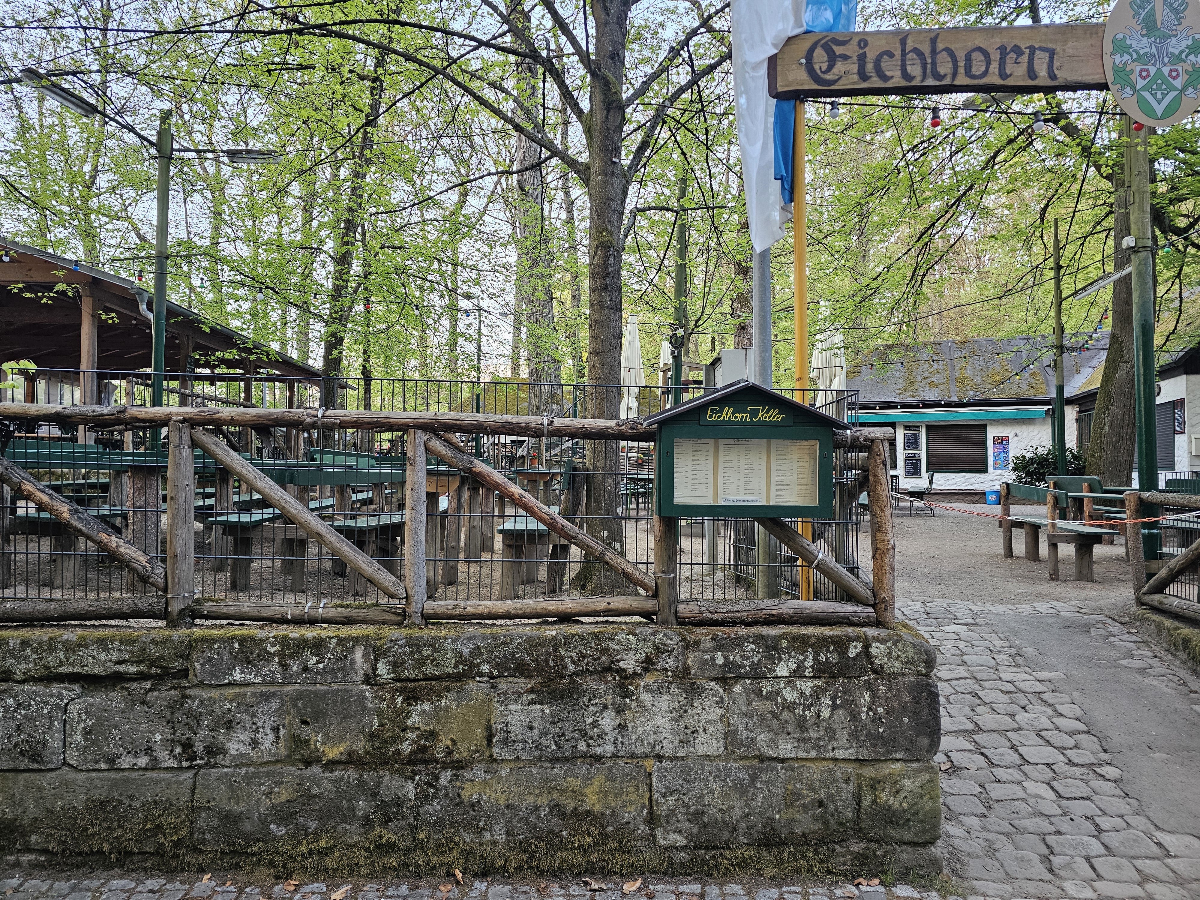 Eingangsbereich zum Eichhornkeller mit Sandsteinmauer und Biergarten-Garnituren im Forchheimer Kellerwald