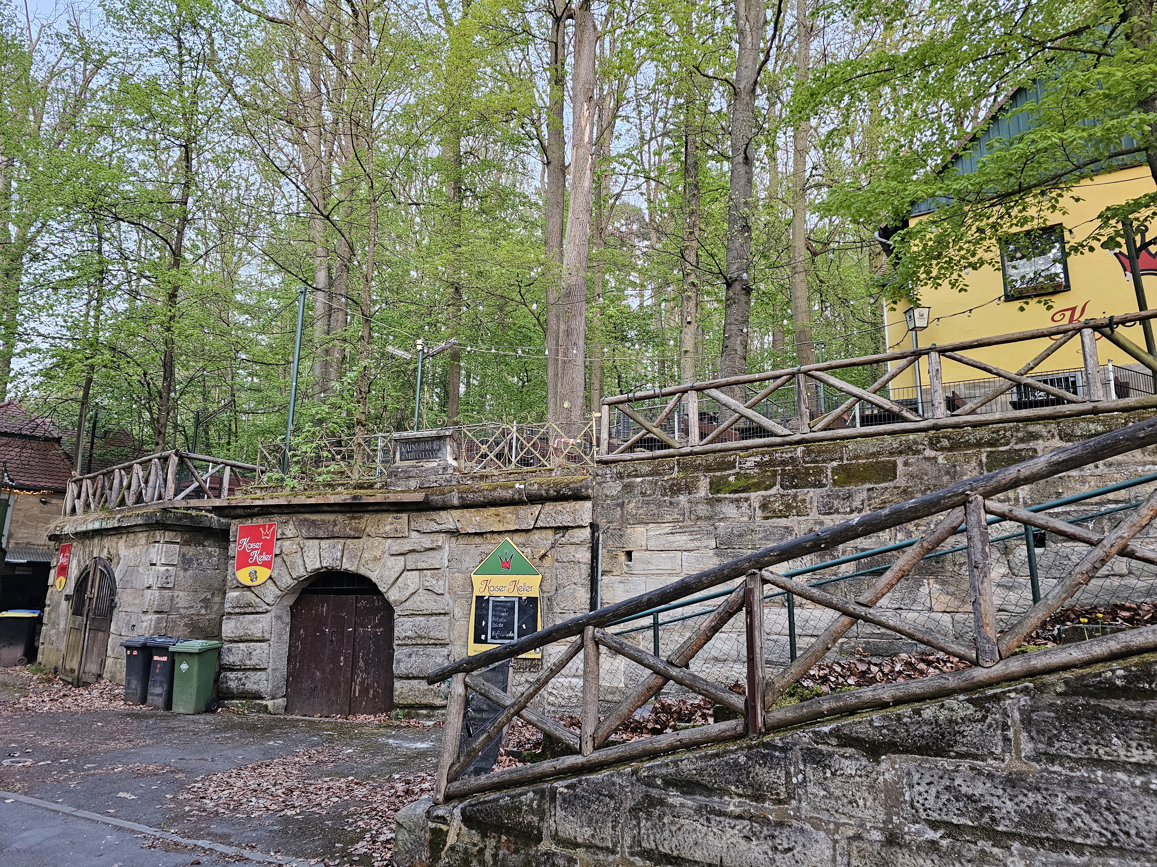 Aufgang zum Kaiser-Keller im Forchheimer Kellerwald, mit Sandsteinmauern, Eingangstor zum Bierkeller für Lagerungen, umgeben von Bäumen.